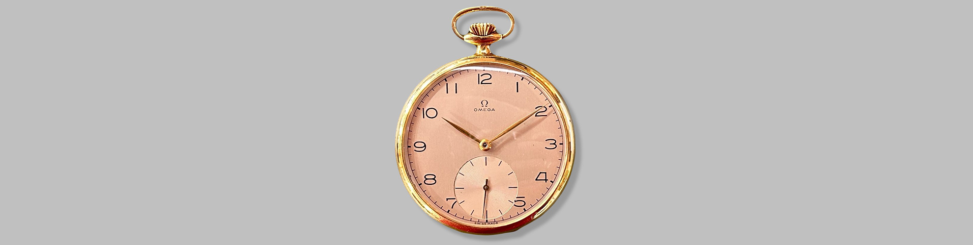 Eine goldene Taschenuhr von Omega mit einem pinkfarbenen Zifferblatt.