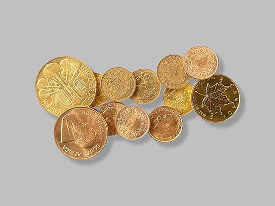 Eine Gruppe goldener Münzen auf grauem Hintergrund. Wertvolle Sammlerstücke aus der Welt der Numismatik. Goldmünzen aus aller Welt.